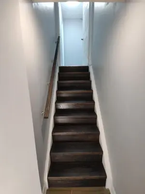 a staircase in a room with wooden floors and white walls at Prestige Accommodation in Ajax