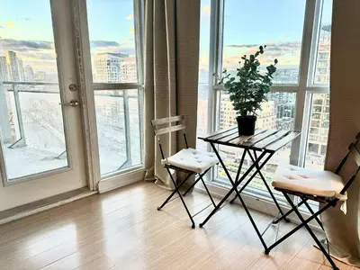 a table and two chairs in a room with a window at Elegant Downtown Condo Near CN Tower -FREE Parking in Toronto