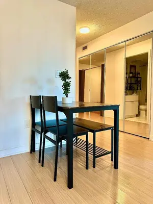 a dining room table with two chairs and a potted plant at Elegant Downtown Condo Near CN Tower -FREE Parking in Toronto