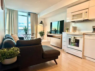 a living room with a couch and a kitchen at Elegant Downtown Condo Near CN Tower -FREE Parking in Toronto