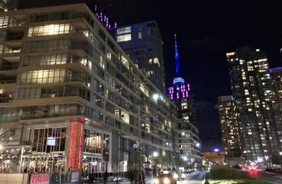 a city at night with a tall building with lights at Elegant Downtown Condo Near CN Tower -FREE Parking in Toronto