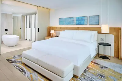 a bedroom with a large white bed and a bath tub at The Pearle Hotel & Spa, Autograph Collection in Burlington
