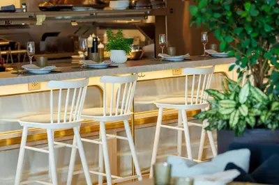 a bar with four white stools in a restaurant at The Pearle Hotel & Spa, Autograph Collection in Burlington