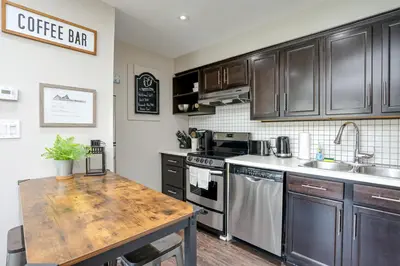 a kitchen with black cabinets and a wooden counter top at Blue Mountain Creekside Studio at North Creek Resort in Blue Mountains
