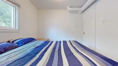 a bedroom with a bed with a blue and white bedspread at Main Beach River Retreat - Wasaga Beach 1 - Main Strip - 95 Mosley St in Wasaga Beach