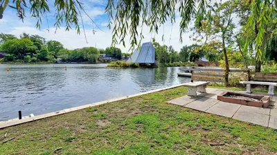 a park bench sitting next to a river with a building at Main Beach River Retreat - Wasaga Beach 1 - Main Strip - 95 Mosley St in Wasaga Beach