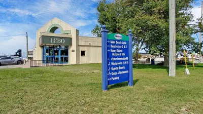 a sign in the grass in front of a building at Main Beach River Retreat - Wasaga Beach 1 - Main Strip - 95 Mosley St in Wasaga Beach