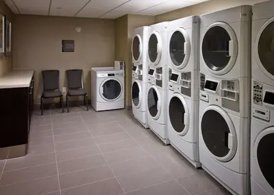 a laundry room with three washes and three chairs at Homewood Suites by Hilton Hamilton in Hamilton