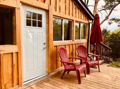 two red chairs and a door on a wooden cabin at The hidden nest in Marmora