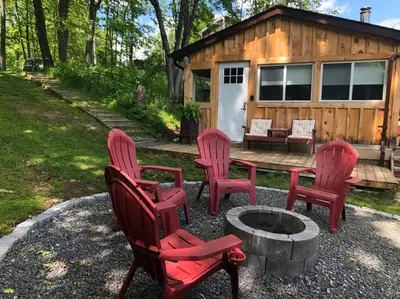 a group of red chairs and a table and a cabin at The hidden nest in Marmora