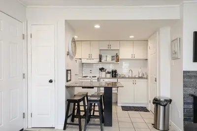 a kitchen with white cabinets and bar stools at Blue Mountain Studio Oasis in Blue Mountains