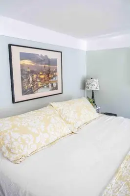 a bedroom with a white bed with a picture on the wall at The Jypsy Inn Chambre Damour Bracebridge in Bracebridge