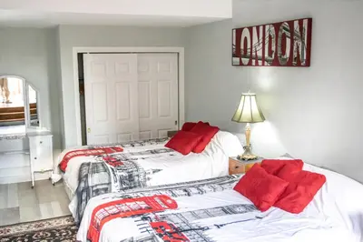 a bedroom with two beds with red pillows on them at The Jypsy Inn Notting Hill in Bracebridge
