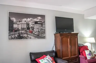a living room with a tv on top of a cabinet at The Jypsy Inn Notting Hill in Bracebridge