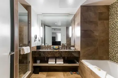 a bathroom with a sink and a tub and a mirror at Sutton Place Hotel Toronto in Toronto