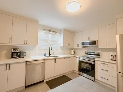 a kitchen with white cabinets and stainless steel appliances at The Promenade Cottage License # 002-2023 in Niagara on the Lake