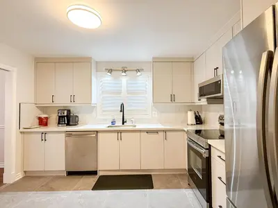 a kitchen with white cabinets and a stainless steel refrigerator at The Promenade Cottage License # 002-2023 in Niagara on the Lake