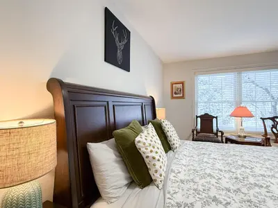 a bedroom with a bed with green and white pillows at The Promenade Cottage License # 002-2023 in Niagara on the Lake
