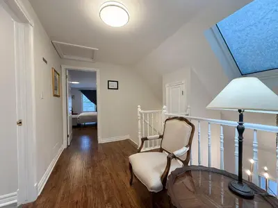 a room with a chair and a table and a lamp at The Promenade Cottage License # 002-2023 in Niagara on the Lake