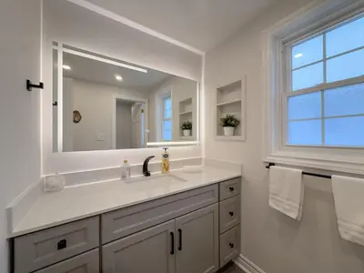 a white bathroom with a sink and a mirror at The Promenade Cottage License # 002-2023 in Niagara on the Lake