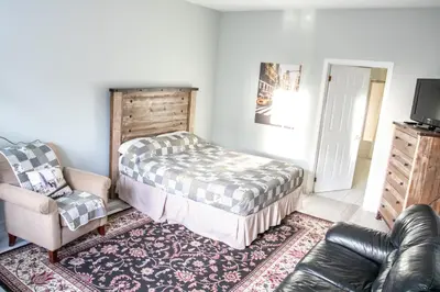 a bedroom with a bed and a chair and a couch at The Jypsy Inn / Fifth Avenue in Bracebridge
