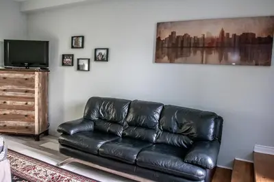a black leather couch in a living room with a television at The Jypsy Inn / Fifth Avenue in Bracebridge