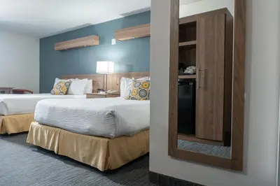a hotel room with two beds and a mirror at Days Inn by Wyndham Niagara Falls Centre St By the Falls in Niagara Falls