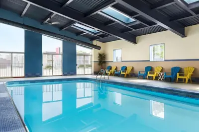 a swimming pool with chairs and tables in a building at Days Inn by Wyndham Niagara Falls Centre St By the Falls in Niagara Falls