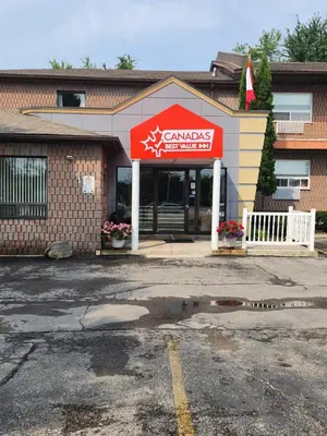 a restaurant with a red sign in a parking lot at Canadas Best Value Inn-Richmond Hill in Richmond Hill