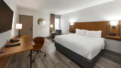 a hotel room with a large bed and a desk at Canadas Best Value Inn Toronto in Toronto