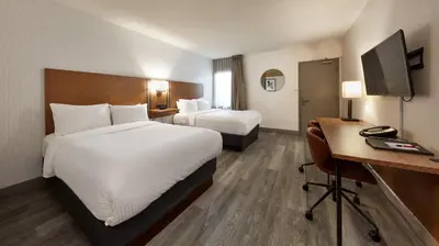a hotel room with two beds and a desk at Canadas Best Value Inn Toronto in Toronto
