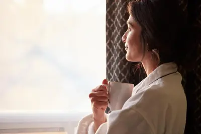 a woman sitting in a chair holding a coffee cup at Stay Inn Hotel Toronto in Toronto
