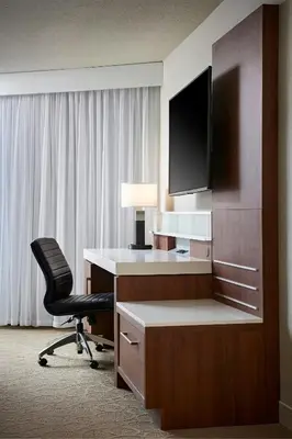 a hotel room with a desk with a television and a chair at Delta Hotels by Marriott Toronto Mississauga in Mississauga