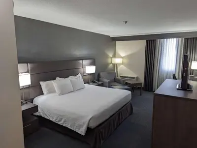 a hotel room with a large bed and a chair at Best Western Plus Toronto Airport Hotel in Mississauga