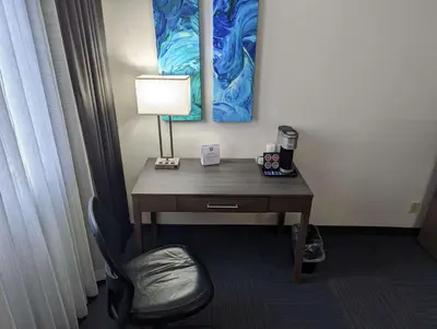 a desk in a hotel room with a lamp and a chair at Best Western Plus Toronto Airport Hotel in Mississauga