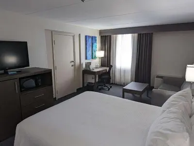 a hotel room with a bed and a television and a desk at Best Western Plus Toronto Airport Hotel in Mississauga