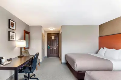 a hotel room with two beds and a desk at Quality Inn Toronto Airport in Mississauga
