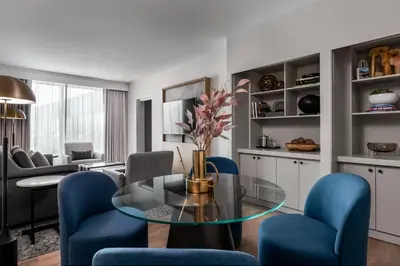 a living room with a glass table and blue chairs at Sheraton Gateway Hotel in Toronto International Airport in Mississauga