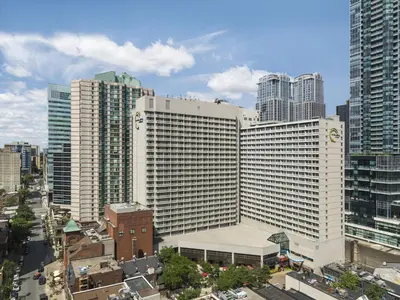 a large white building in a city with tall buildings at Chelsea Hotel Toronto in Toronto