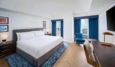 a bedroom with a large bed and a desk and a chair at Pantages Hotel Toronto Centre in Toronto