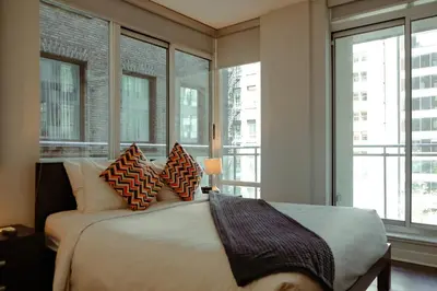 a bedroom with a large bed with pillows and windows at Executive Hotel Cosmopolitan Toronto in Toronto