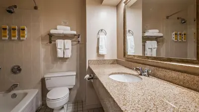 a bathroom with a sink and a toilet and a mirror at Best Western Plus Cairn Croft Hotel in Niagara Falls