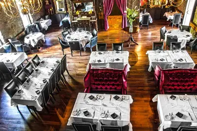 a dining room with white tables and red chairs at Old Stone Inn Boutique Hotel in Niagara Falls
