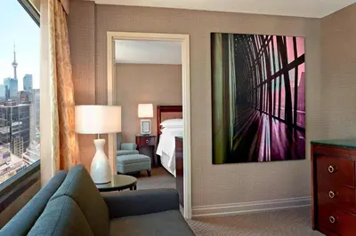 a hotel room with a bed and a couch and a mirror at Sheraton Centre Toronto Hotel in Toronto