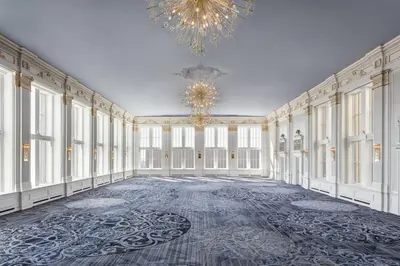 an empty room with a chandelier and a large room with white walls at The Omni King Edward Hotel in Toronto