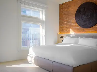 a bedroom with a white bed and a brick wall at Gladstone House in Toronto