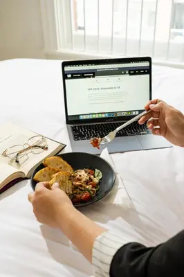 a person sitting at a table with a plate of food and a laptop at Gladstone House in Toronto