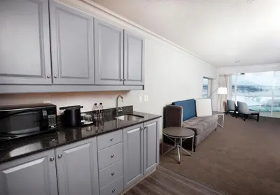 a kitchen with white cabinets and a living room with a couch at Niagara Falls Marriott on the Falls in Niagara Falls