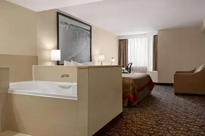 a hotel room with a tub and a bed at Ramada By Wyndham Niagara Falls near the Falls in Niagara Falls