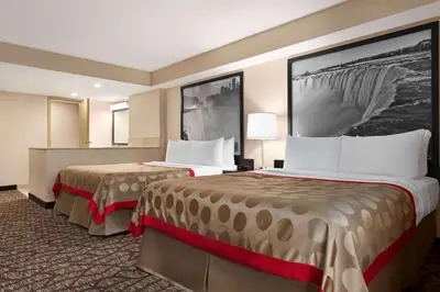a hotel room with two beds in a room at Ramada By Wyndham Niagara Falls near the Falls in Niagara Falls